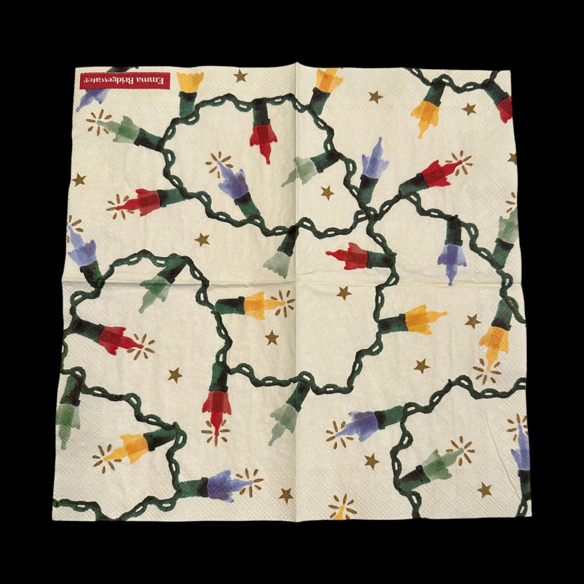 Open Christmas string light decoupage napkin featuring colorful red, yellow, green, and blue bulbs with glowing accents and small gold stars on a cream background.