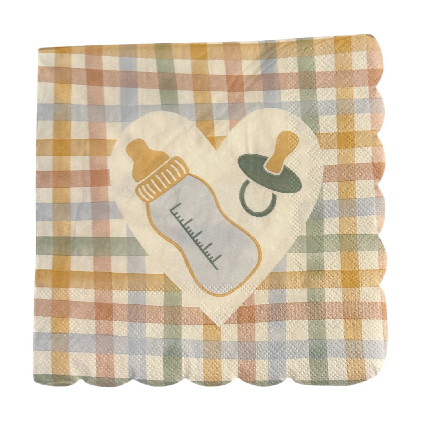 Close-up of a scalloped-edge luncheon napkin featuring a pastel gingham pattern in yellow, peach, blue, and green with a white heart in the center displaying a baby bottle and pacifier design.