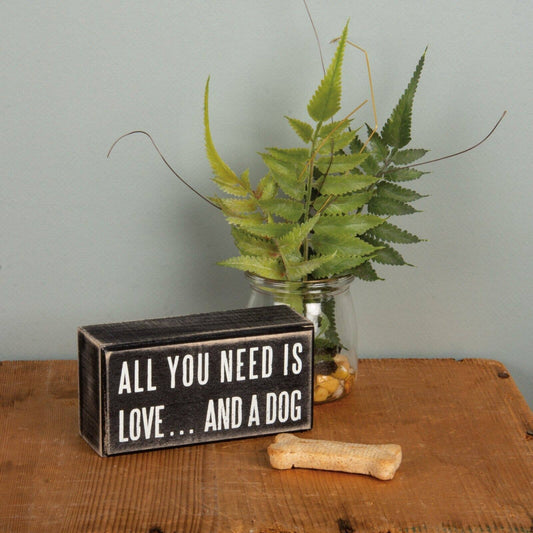 a wooden black box sign with white lettering that says All you need is love...and a dog